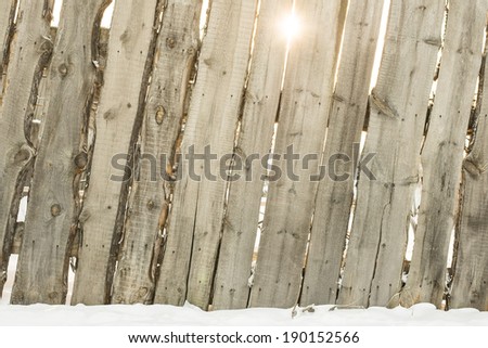 Background of old Wooden fence and  winter clear snow Sun shine rays through gap cold gate