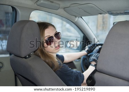 woman in car indoor keeps wheel turning around smiling looking at passengers in back seat idea taxi driver talking to police companion companion who asks for directions right to drive Documents exam