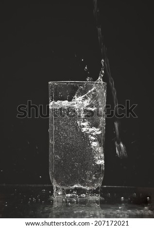 pouring cold water in simple highball glass, Object isolated on black background  Empty above copy space for inscription