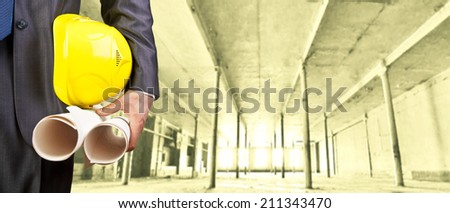 torso engineer or worker hand holding yellow helmet for workers security over empty room indoor old building inside warehouse background Copy Space for inscription