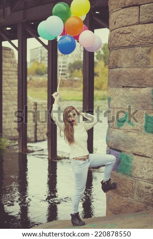 Vintage photo Full length portrait  of woman having fun with colorful balloons on water texture under stone old retro vintage bridge background Young girl wearing casual dress and looking at camera