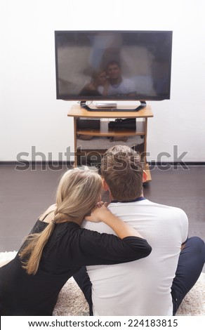 Back view girl friend  sits and rests on a strong sholder boyfriend  on the floor on TV background on white wall - couple embracing with each other Woman based near Man black and white casual dressed