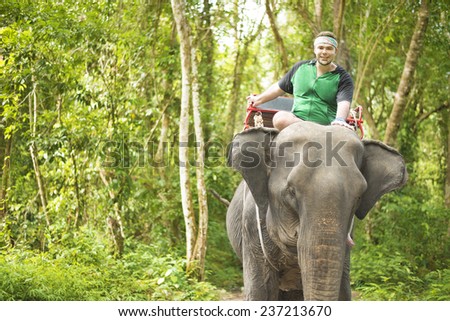 Unidentified elephant handler preparing his received one tourist for jungle ride in Thailand Man ride on an wild animal in green summer forest at Chiang mai Empty copy space for inscription
