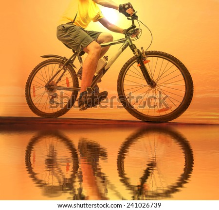 Unrecognizable person No face Mountain Biker on sky with clouds background Man wear yellow sport shirt gray snickers and shorts Empty copy space for inscription Reflection sun on yellow water texture
