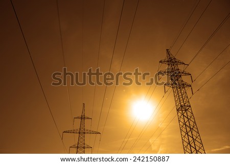 Background of Pylon and power lines at sunset with red sky with clouds and sun shine rays