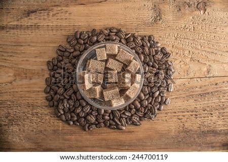 brown sugar in glass transparent round bowl with grilled coffee beans around on old retro vintage aged texture background