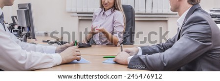 No face Unrecognizable person Three business people sitting at table with papers and pc computer and planning against texture window in wall background Woman sit in leather armchair near keyboard