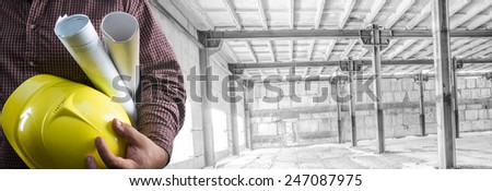 No face Unrecognizable person construction worker man hold in hand blueprint yellow helmet on empty old building inside concrete warehouse background Copy Space for inscription Idea concept of safety