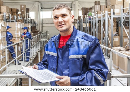 warehouse three workers- one man and two woman in a special blue uniform is recording and accounting of contents in cardboard boxes in stock Idea account statistics rediscount cargo arrival