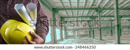No face Unrecognizable person construction worker man hold in hand blueprint yellow helmet on empty old building inside concrete warehouse background Copy Space for inscription Idea concept safety