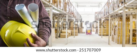 No face Unrecognizable person construction worker man holding in hands blueprint and yellow helmet against shelf box on warehouse in perspective background Empty copy space for inscription