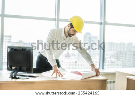 businessman architects look at paper plan business man architect near computer pc monitor in office to discuss business projects. Successful young engineer in construction yellow helmet are on table