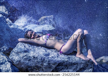 Young adult sexy hot woman dream and lie snowy freeze stone mountain dark blue sky wild nature night background under fly snowflake Empty space for inscription Closed eyes Hand under head