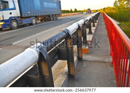 truck on cross-sea red metal bridge against on blue sunset sky background Mountain Highway With Oncoming Trucks In A Wooded Area