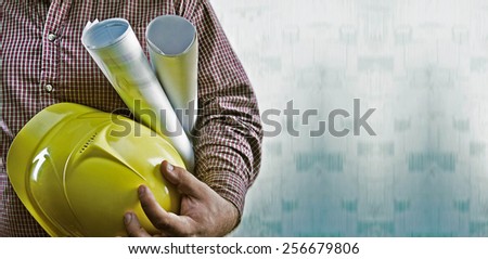 No face Unrecognizable person construction worker man holding in hands blueprint and yellow helmet on green texture wall with wallpaper background Empty copy space for inscription