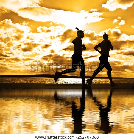 silhouette of two women running at sunset or sunrise Girl move along sun set sunny beach Reflection light on water texture  Couple Doing sports exercises against sky with clouds