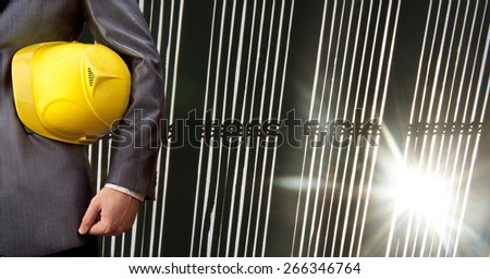torso engineer or worker hand holding yellow helmet for workers security over sun light rays between jalousie office window background Empty space for inscription against sunset