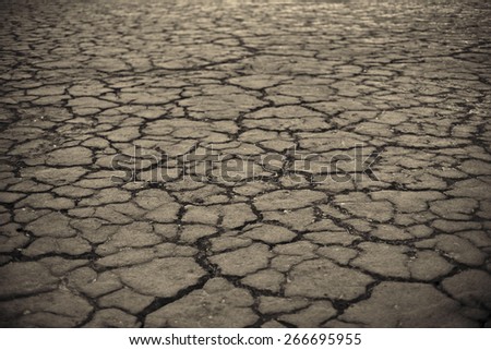 Dry lake bed with natural texture of cracked clay in perspective floor. Death Valley  field .  background. Selective focus on black soil dark land. Idea concept symbol disaster ecology in nature