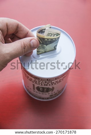 man Hand load money to moneybox bank, isolated on red texture  background Finger keep 50 fifty dollar bill Empty space for inscription