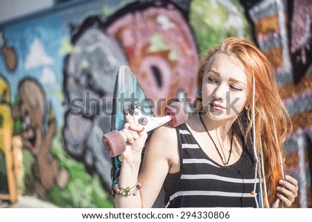 Portrait of Beautiful redhead caucasian teen girl with long skate board stand against graffiti style wall. Outdoors, urban lifestyle. Empty space for inscription. Youth subculture
