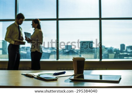 Couple of business man, woman talk about document Object tool in office room tablet computer paper cup with hot coffee Cell mobile phone Paper document lie on table against blue sky window with houses