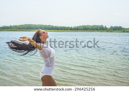 Beautiful alone Asian girl enjoying with closed eyes Happy young adult woman on summer beach, pretending to fly with arms wide open, enjoying freedom and sun. Empty space for inscription Water texture