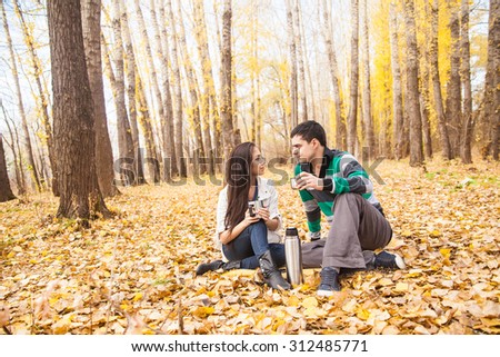 Happy young adult latin hispanic couple sit on a yellow plaid in autumn dry city park looking each other Empty copy space for inscription or objects Handsome man hold in hand cup with hot coffee