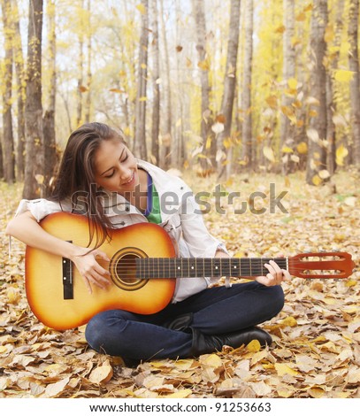 girl plays guitar in the autumn forest