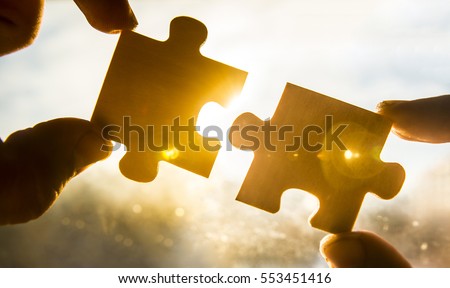 two hands trying to connect couple puzzle piece with sunset background. Jigsaw alone wooden puzzle against sun rays. one part of whole. symbol of association and connection. business strategy.  Сток-фото © 