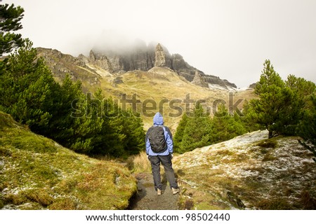Woman walker hiker standing looking at the Old Man Of Storr on the Isle Of Skye Scotland