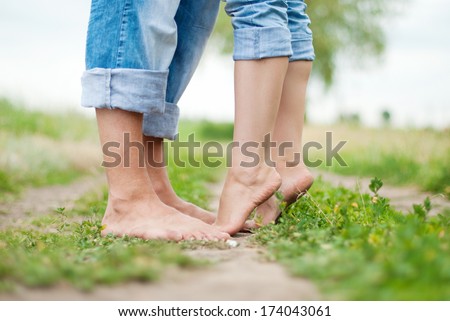 Happy couple on a walk in summer. Woman and men feet on green grass. Healthy lifestyle.