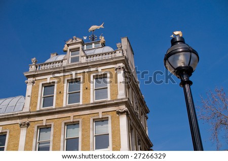 Top corner of a building against blue sky - A photography of the top right corner of a building against blue sky, with a Lamp post in the foreground.
