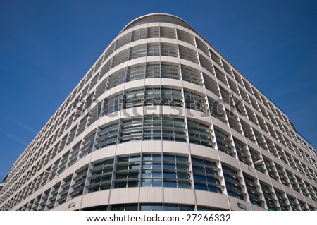 Corner of smart looking building against blue sky - Photograph of a round corner of a smart looking building, shot against a clear blue sky.