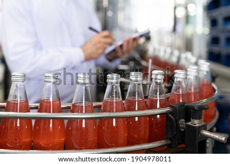Hands of male worker writing notes about product of Basil seed with fruit on the conveyor belt in the beverage factory. Worker checking bottling line for processing. Inspection quality control Сток-фото © 