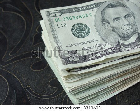 Stack of five dollar bills spread