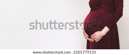 Pregnant woman in bordo dress touching belly, preparing go to maternity hospital for childbirth. Pregnancy, maternity, preparation, baby expectation concept. 40 weeks of pregnancy. White background. Stok fotoğraf © 
