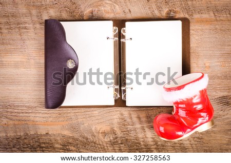 Santa Claus boots and blank wish book on wooden background, New Year and Christmas decoration, card. Free space for text.