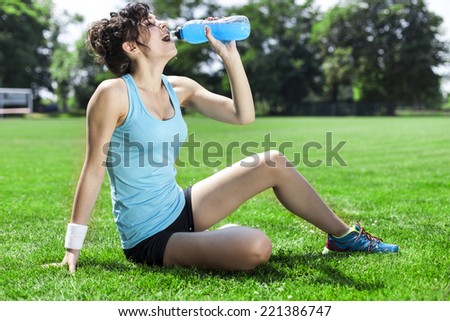 Tired woman runner taking a rest after run, drinking water