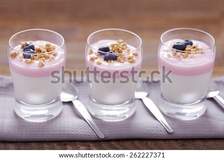 Delicious dessert, flakes flooded in two flavors yogurt with blueberries and fruit on a wooden board. dSLR photo