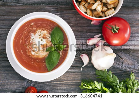 Delicious tomato soup with aromatic spices on a wooden table. Studio shot