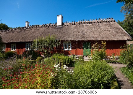 old wooden scandinavian house with straw roof and beautiful garden
