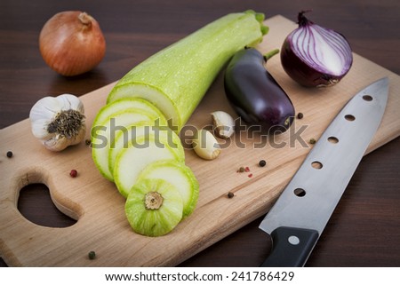 Zucchini, garlic, onion and eggplant on a board in the kitchen
