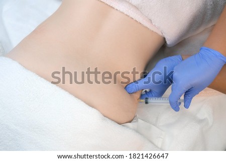Doctor makes injection of ozone gas in patient abdomen on side on ozone therapy, closeup top view. Treatment, cure and remove of skin tags and stretches. Cosmetologist woman in gloves.