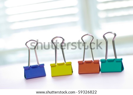 Colorful binder clip on white table near white window. long-tail clip, one kind of stationery.