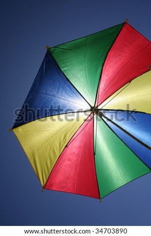 flying multicolored umbrella on clear blue sky