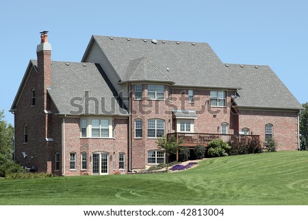 Rear view of large brick home with deck