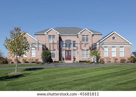 Large brick home in suburbs with red door