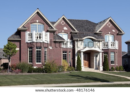 Luxury brick home in suburbs with front bedroom balconies