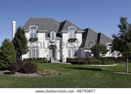 White brick home in suburbs with arched entry
