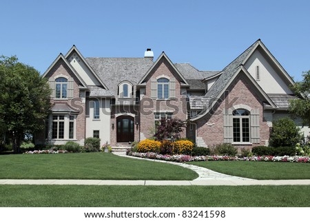 Large brick home with a variety of flowers